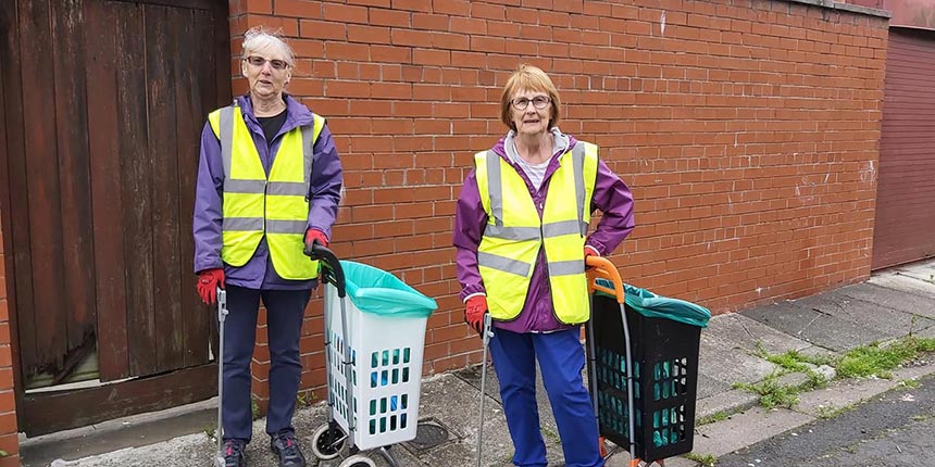 Two ladies wearing High-vis jackets collecting litter
