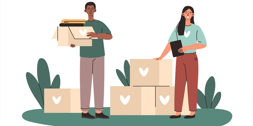 Two people packing cardboard boxes with donations.