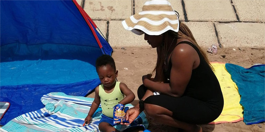 Mother and child playing on sand in the sun